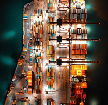 pexels photo 8777703 Dramatic aerial view of a busy shipping port with colorful containers and bright lights at night.